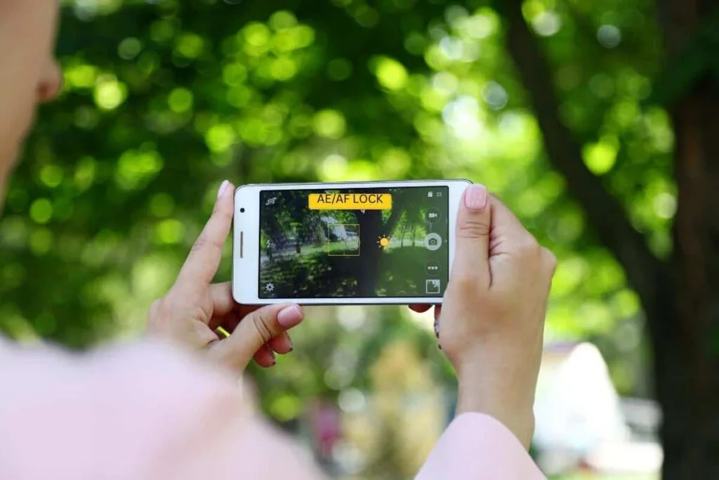 A person taking a picture with an iPhone showing the AE/AF Lock and Focus box as an example of how to take a good photo on iPhone.