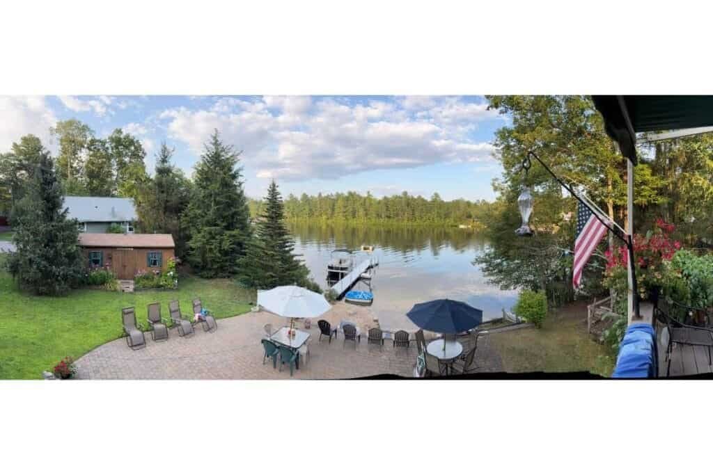 How to take a good photo on iPhone using Pano Mode (1) A lake with a boat, and beach area with chairs and tables and a panoramic example of how to take a good photo on iPhone.