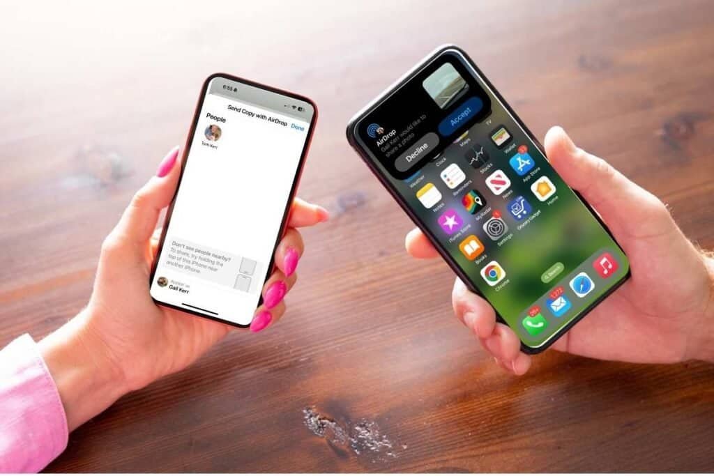 Two people holding an iPhone, one is sending a photo using AirDrop and the other iPhone was notification to accept photo as an example of AirDrop on iPhone.