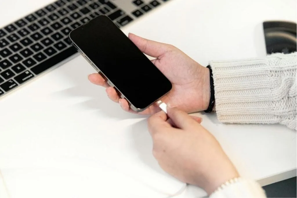 An iPhone getting plugged in to charger as an example of battery drain problem in ios 26