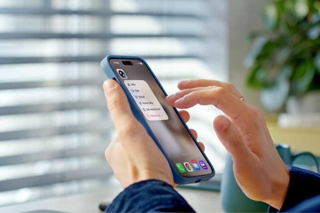 An iPhone in hand pressing on the camera iPhone Quick Actions Shortcut