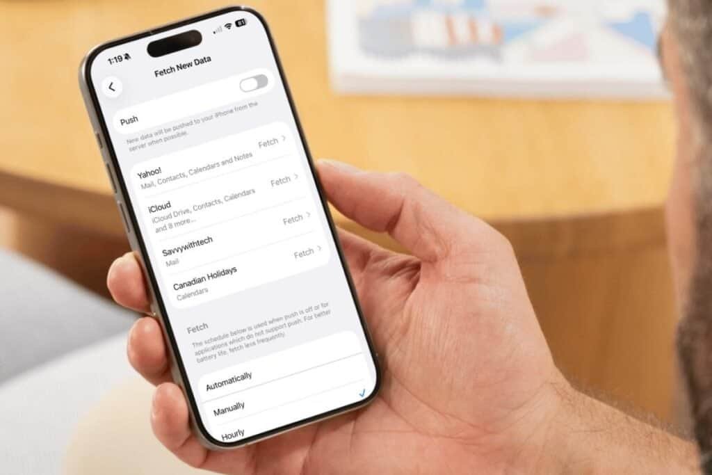 Fetch vs Push can prevent iPhone battery draining fast A hand holding an iPhone showing the mail settings using Fetch to help prevent iPhone battery draining fast.