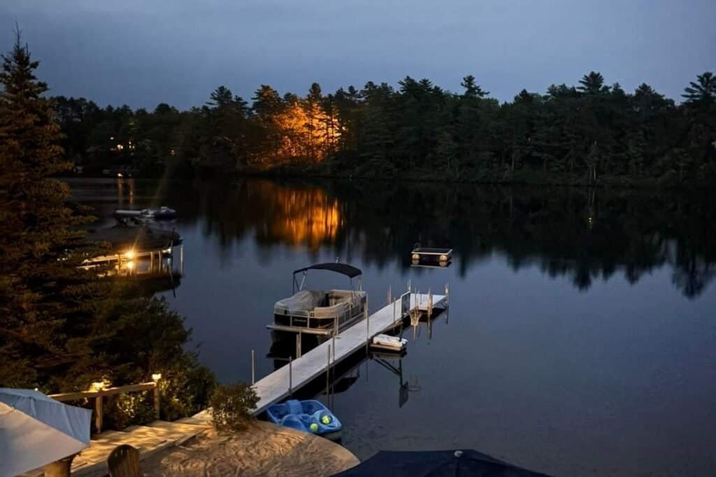 Low light photo of a lake with a boat and dock.